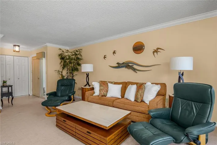 Living area featuring crown molding, a textured ceiling, and light colored carpet