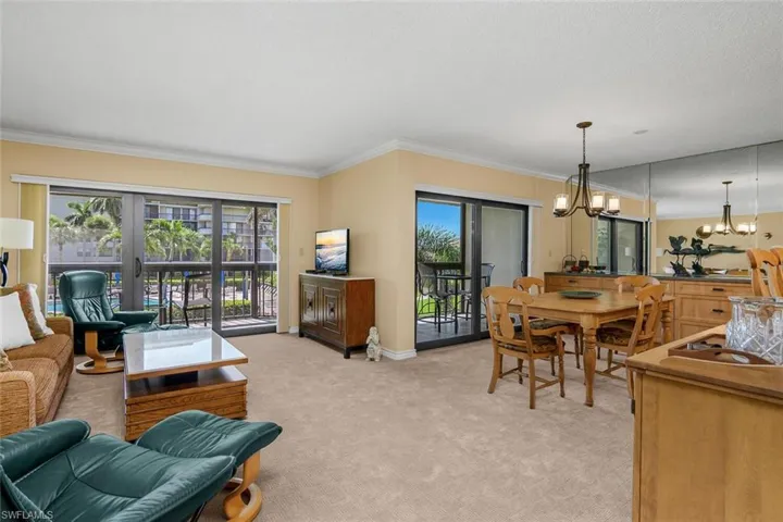 Living area with a chandelier, ornamental molding, light carpet, and french doors