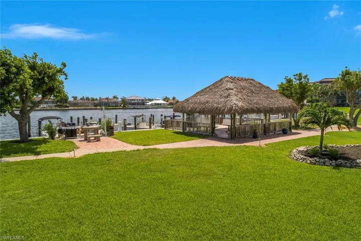 View of property's community featuring a yard, a gazebo, a water view, and a boat dock
