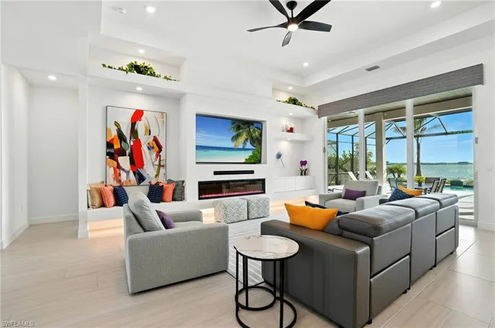 Living room featuring a sunroom, recessed lighting, a glass covered fireplace, and a ceiling fan