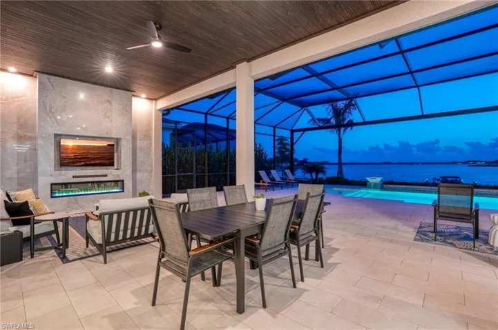 View of patio / terrace featuring glass enclosure, a water view, a sunroom, an outdoor pool, and outdoor dining space