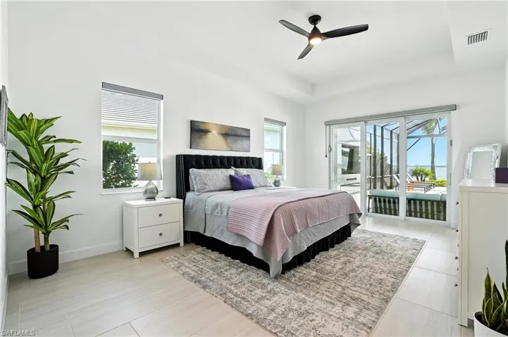 Bedroom featuring access to exterior, a ceiling fan, a sunroom, and a tray ceiling