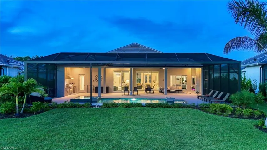 Back of house at dusk featuring a sunroom, a lanai, a patio, and a yard