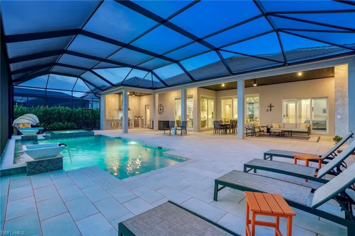 View of pool featuring a sunroom, ceiling fan, a pool with connected hot tub, glass enclosure, and a patio area