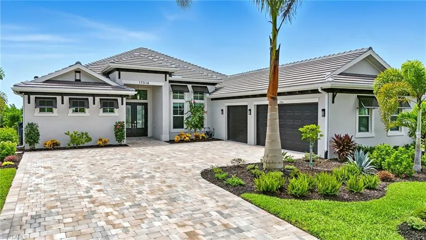 View of front of house with a garage, stucco siding, decorative driveway, french doors, and a tiled roof