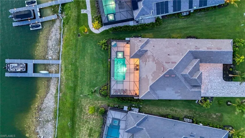 Aerial view of property and surrounding area with a pool area and a large body of water