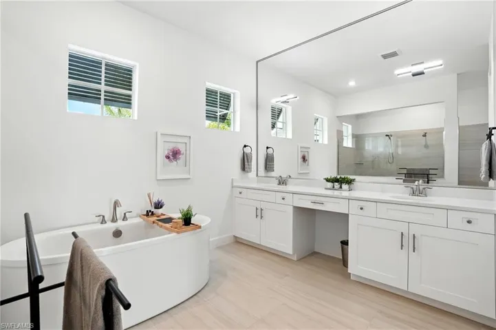 Full bathroom featuring walk in shower, double vanity, and a freestanding bath
