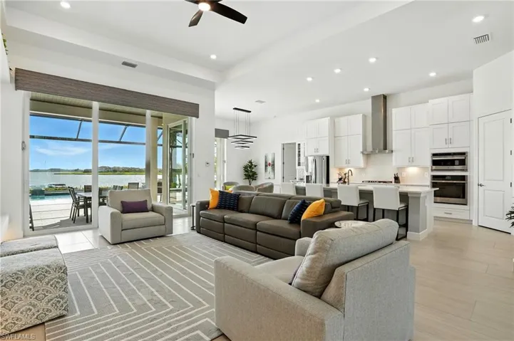 Living room featuring recessed lighting, a water view, a ceiling fan, and a sunroom