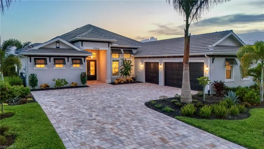 View of front facade featuring an attached garage, stucco siding, decorative driveway, and a tiled roof