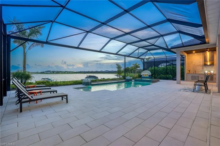 Outdoor pool featuring a jacuzzi, a sunroom, a patio, and glass enclosure
