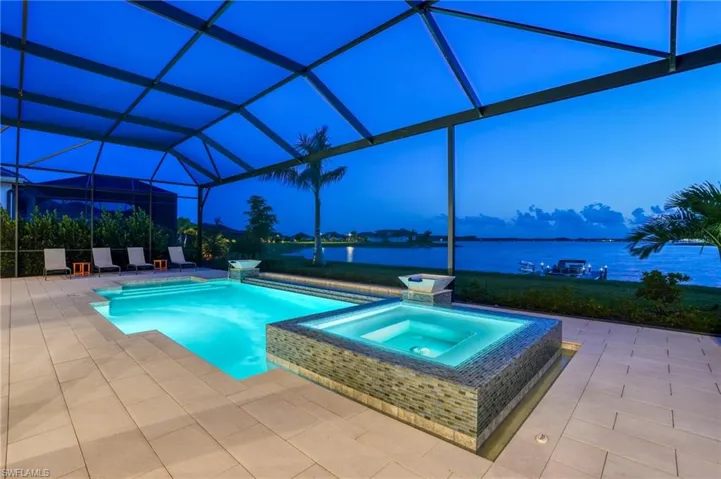 View of swimming pool with a water view, a patio, a pool with connected hot tub, glass enclosure, and a sunroom