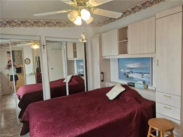 Bedroom with two closets, a ceiling fan, and tile patterned floors