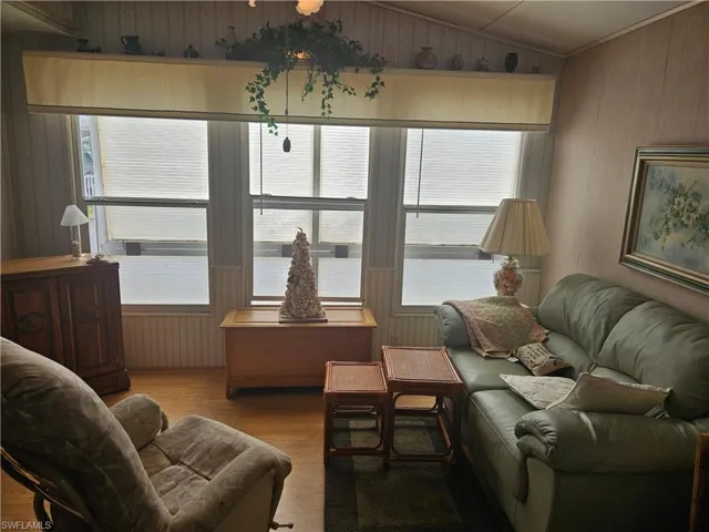 Living room with wood finished floors, wood walls, and vaulted ceiling