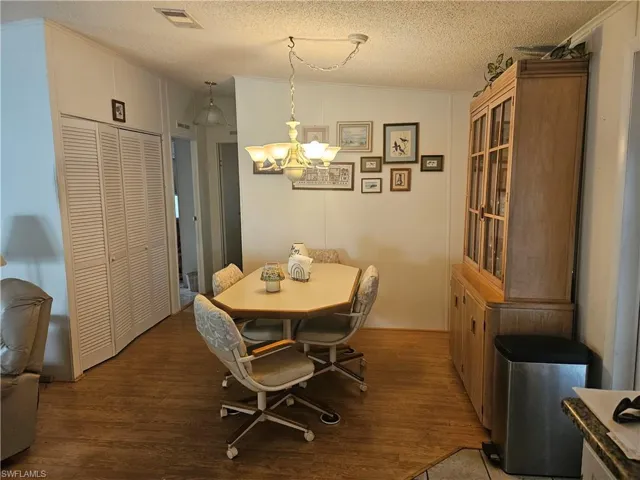 Dining space with visible vents, an inviting chandelier, wood finished floors, and a textured ceiling