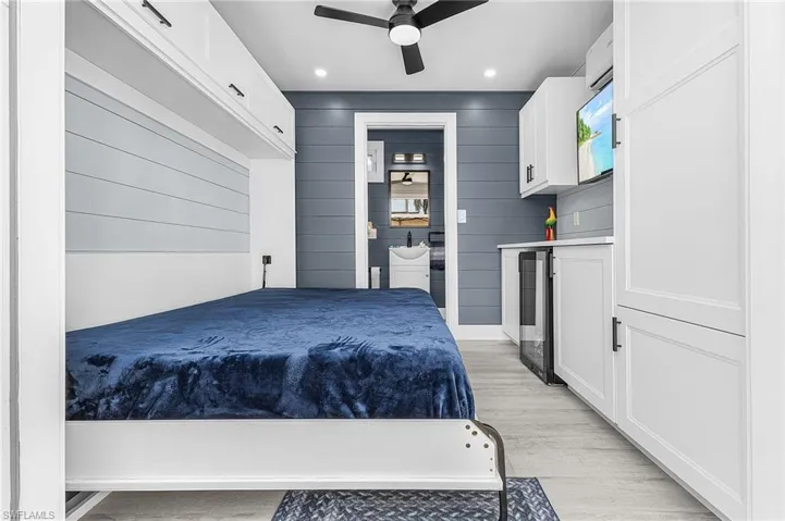 Bedroom featuring beverage cooler, recessed lighting, wood walls, ceiling fan, and light wood-style flooring