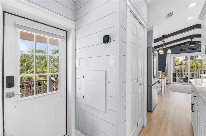Entryway with wood finished floors, vaulted ceiling with beams, ceiling fan, recessed lighting, and wood walls