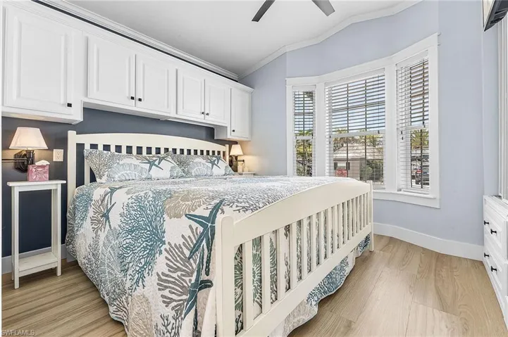 Bedroom with crown molding, light wood-style floors, vaulted ceiling, and a ceiling fan