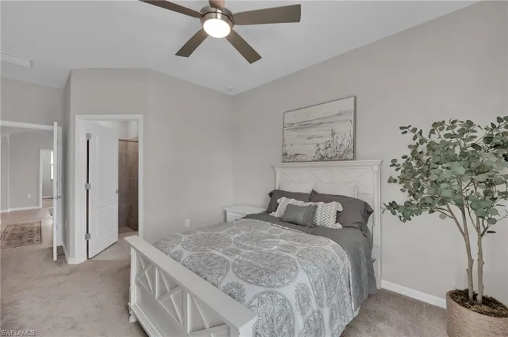 Bedroom featuring ensuite bathroom, light colored carpet, and ceiling fan
