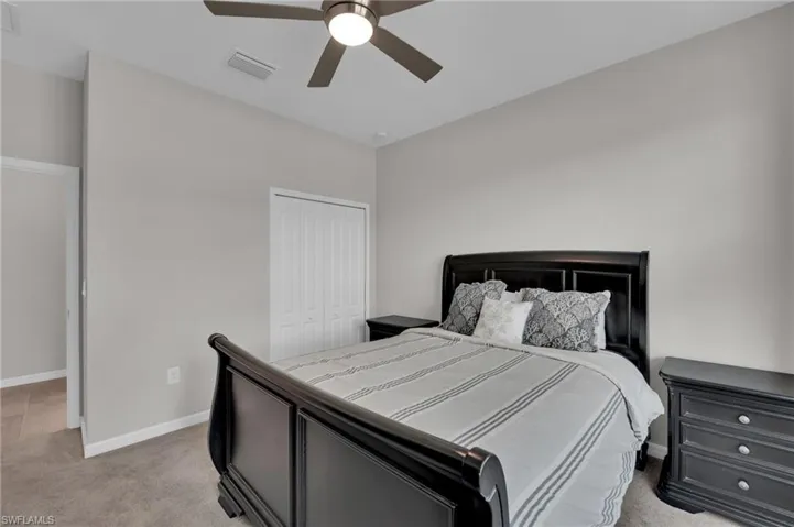 Bedroom featuring light carpet, a ceiling fan, and a closet
