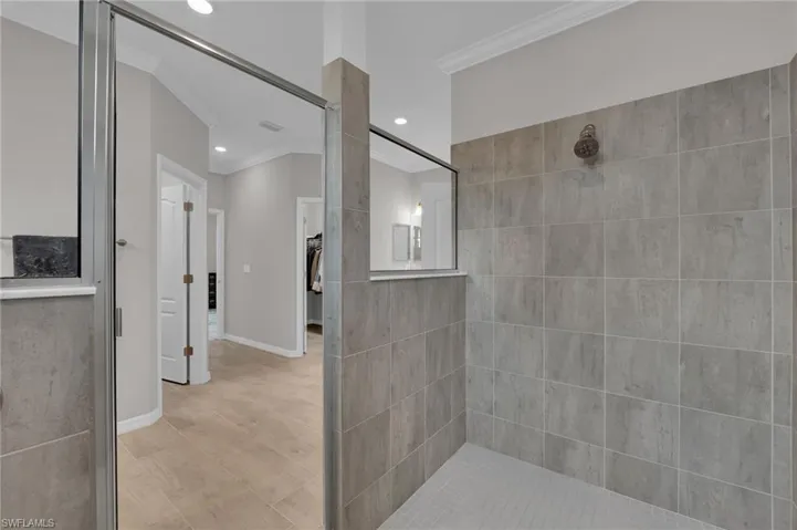 Full bath featuring crown molding, a tile shower, a spacious closet, and recessed lighting