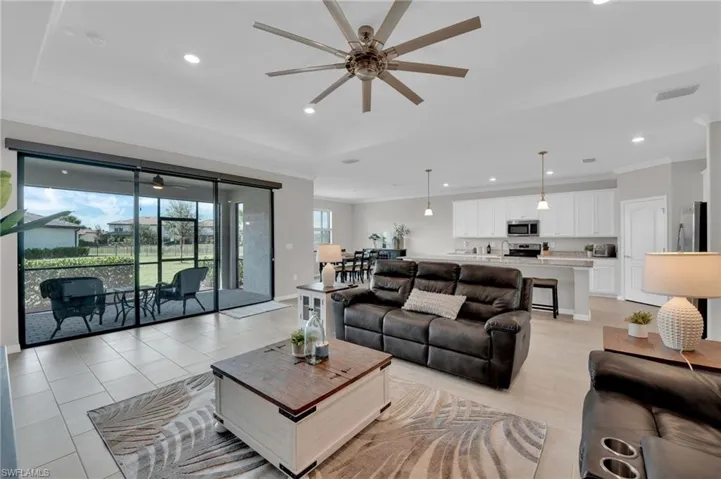 Living room featuring ceiling fan, recessed lighting, ornamental molding, a sunroom, and a tray ceiling