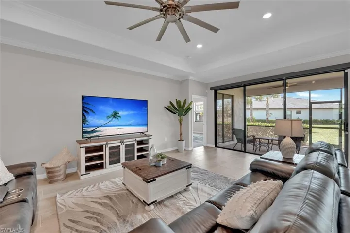 Living room with a ceiling fan, recessed lighting, a tray ceiling, and ornamental molding