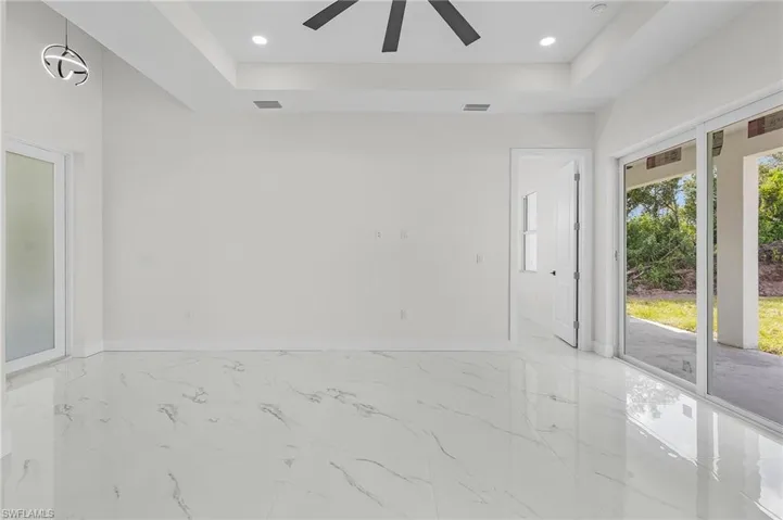 Tiled empty room with ceiling fan and a raised ceiling