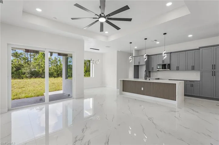 Kitchen featuring sink, a kitchen island with sink, gray cabinetry, light tile patterned floors, and a raised ceiling