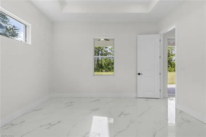 Spare room featuring a raised ceiling, a healthy amount of sunlight, and tile patterned floors