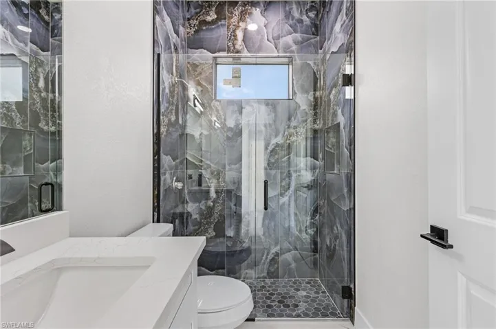 Bathroom featuring an enclosed shower, vanity, and toilet