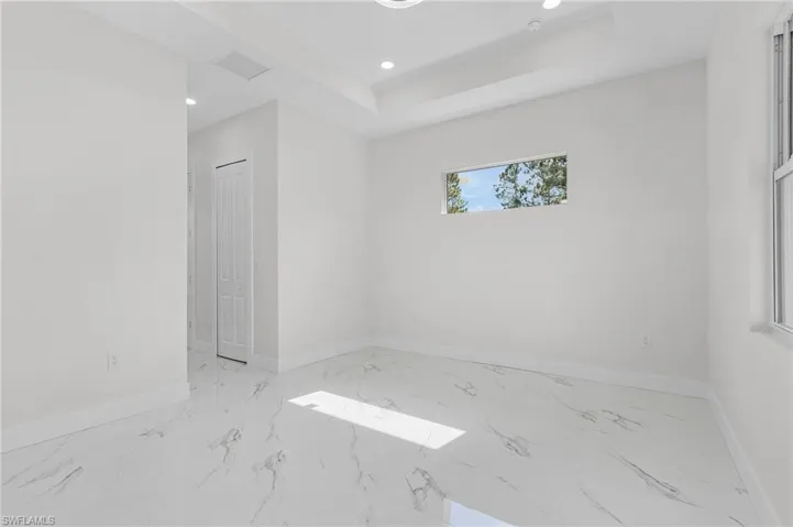 Unfurnished room with a tray ceiling and light tile patterned floors