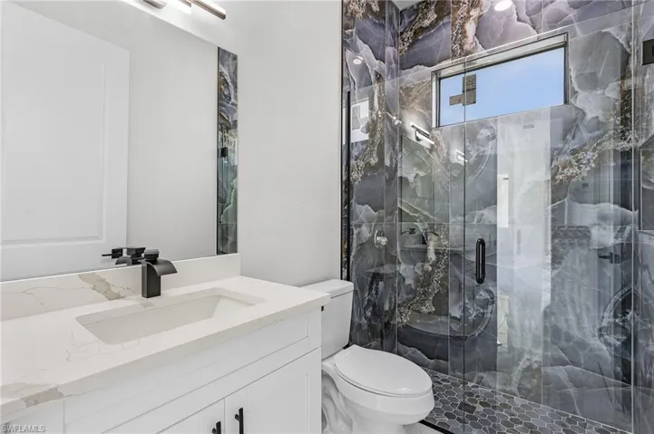 Bathroom with toilet, vanity, and walk in shower