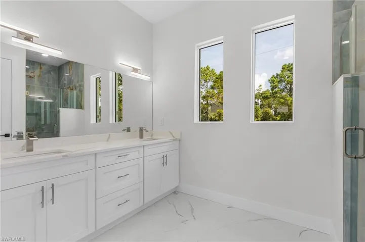Bathroom featuring double sink vanity, tile patterned flooring, and a shower with shower door