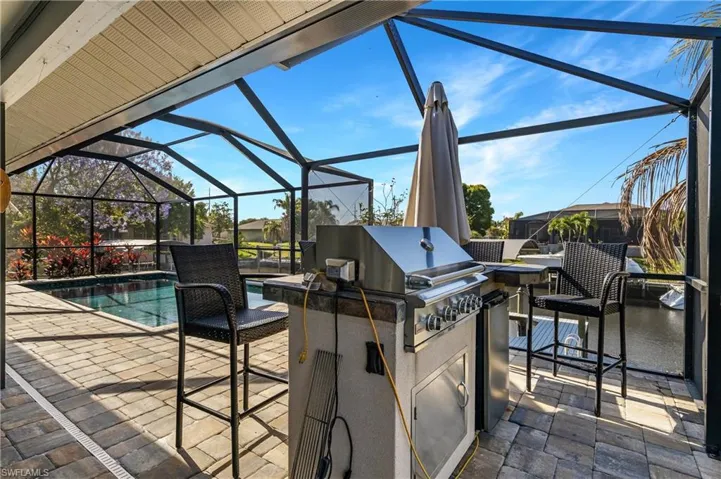 View of patio / terrace with glass enclosure, exterior kitchen, a sunroom, and an outdoor pool