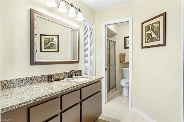 Bathroom with a stall shower, vanity, light tile patterned flooring, and a closet