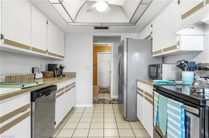 Kitchen with white cabinetry, light countertops, stainless steel appliances, and ceiling fan