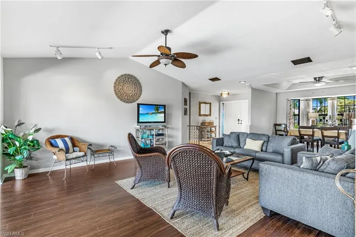 Living room with rail lighting, ceiling fan, and wood finished floors
