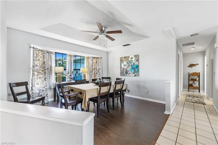 Dining space with a tray ceiling, a ceiling fan, and dark wood-type flooring