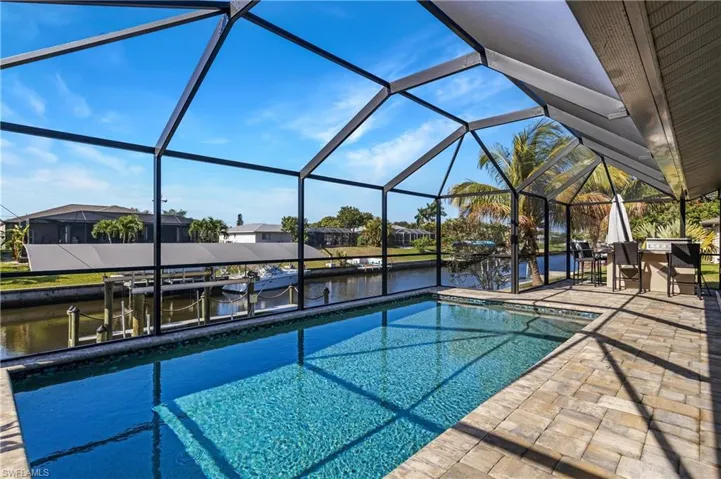 Swimming pool with a water view, a sunroom, a lanai, a residential view, and a patio