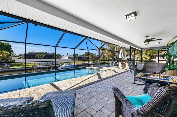 Swimming pool with a patio, a lanai, a sunroom, an outdoor fire pit, and a dock