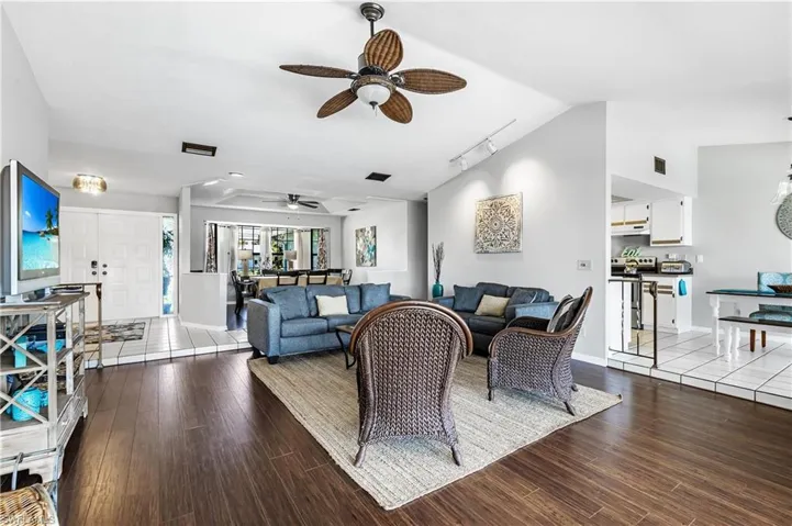Living area featuring lofted ceiling, dark wood finished floors, rail lighting, and a ceiling fan
