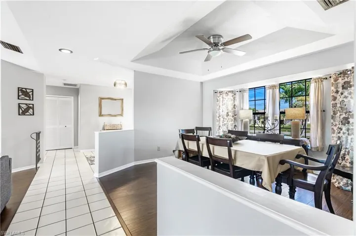 Dining space with a tray ceiling, a ceiling fan, and dark wood-style flooring