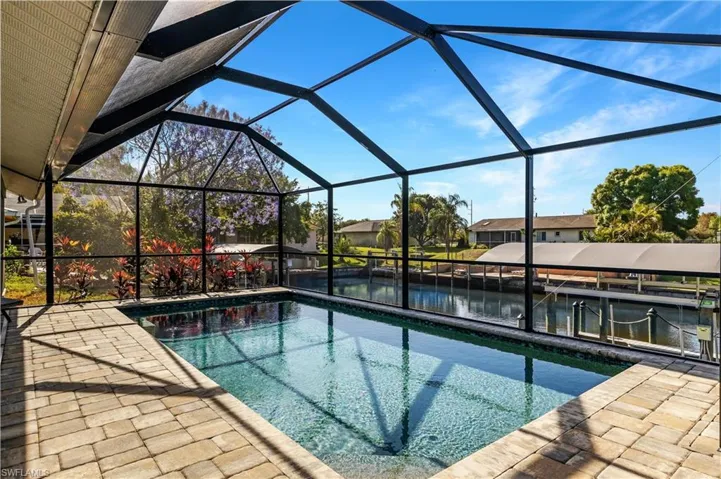 Swimming pool featuring a sunroom, glass enclosure, a water view, and a dock