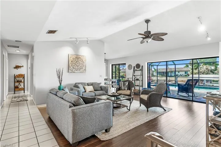 Living area featuring track lighting, a ceiling fan, wood finished floors, a sunroom, and lofted ceiling