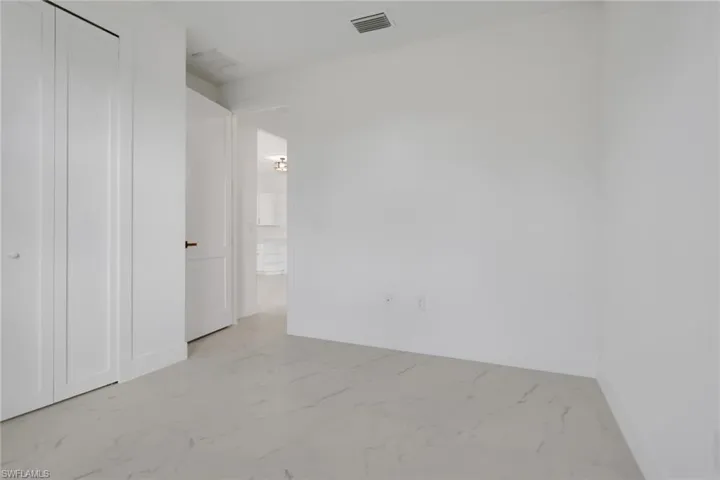 Guest bedroom 1 featuring light marble finish floors and a closet