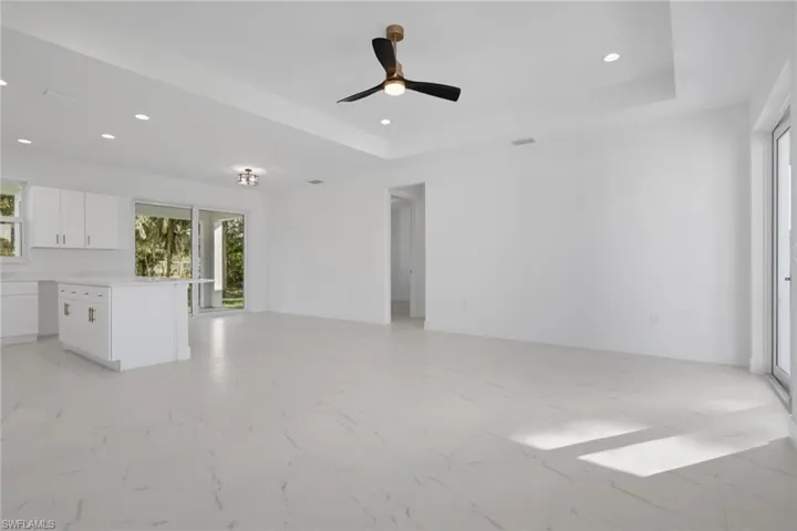 Unfurnished living room featuring light marble finish floors, recessed lighting, a raised ceiling, and ceiling fan