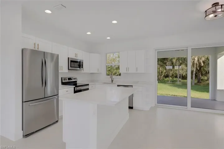 Kitchen featuring stainless steel appliances, white cabinetry, recessed lighting, a kitchen island, and open shelves