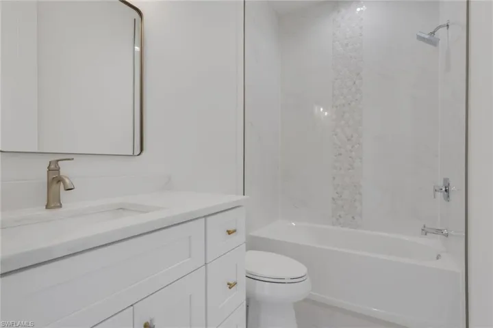 Guest bath with vanity, tub / shower combination, and light marble finish flooring