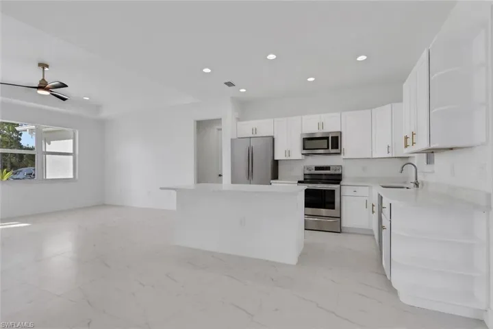 Kitchen featuring a kitchen island, stainless steel appliances, recessed lighting, white cabinetry, and open floor plan