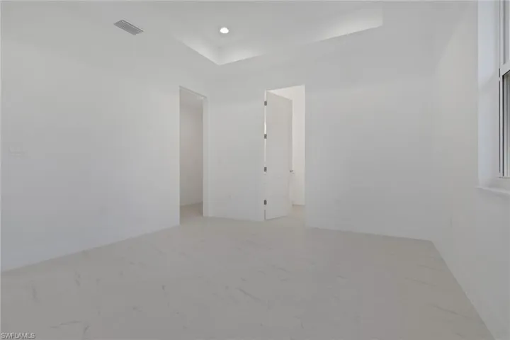 Primary bedroom with light marble finish floors and recessed lighting with view and walk-in closet and bathroom